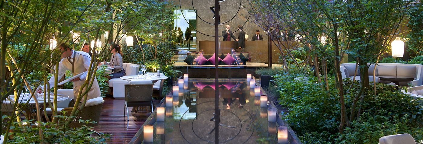 Mandarin Oriental Paris on Rue Saint-Honoré with the dedicated interior garden courtyard illuminated in the evening — the substantial green oasis at the heart of the 1st arrondissement luxury shopping district