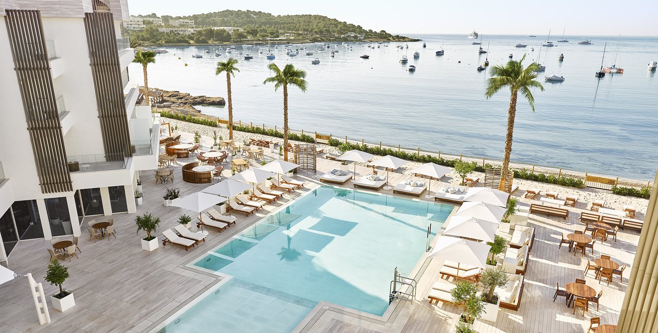 Nobu Hotel Ibiza Bay on Talamanca Bay with the Mediterranean view across to Ibiza Town and the substantive beachfront pool configuration — the only Nobu Hotel in the Balearic Islands