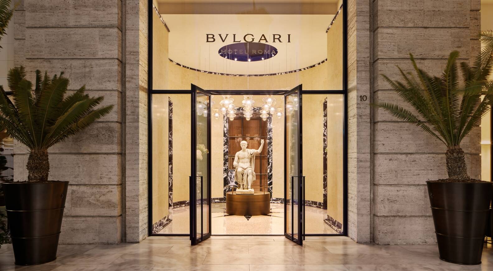 The Bulgari Hotel Roma vestibule with the substantial first-century-BC marble statue of Augustus and the dedicated Fior di Pesco marble detailing evocative of the property's specific contemporary-Roman luxury configuration